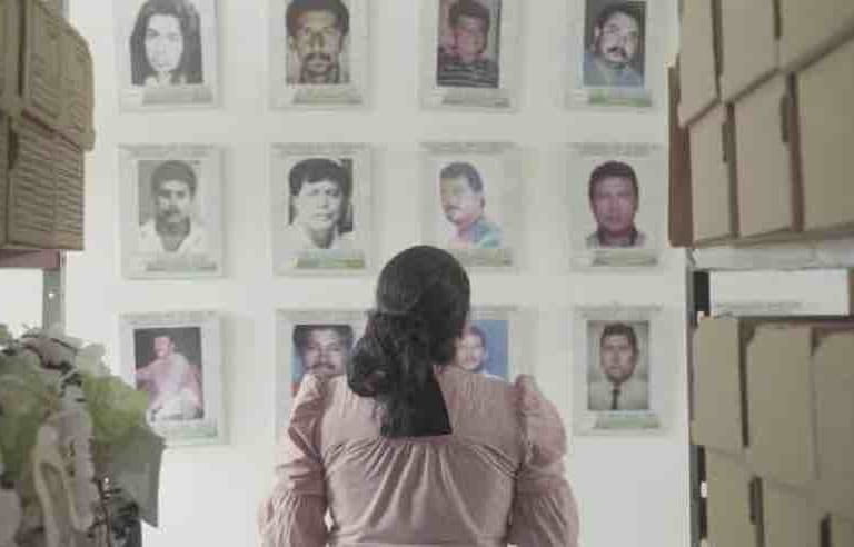 Yuli Velázquez, representante legal de la organización ambientalista FEDEPESAN, mira las fotos de defensores asesinados en Barrancabermeja, Colombia, en 2022. Foto: cortesía Negrita Films/Global Witness